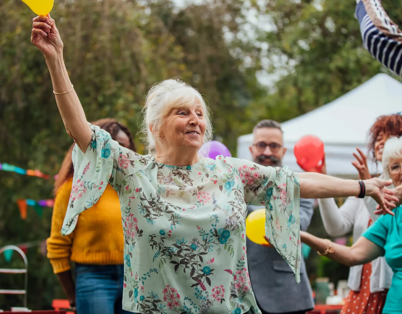 Senior woman celebrating joyfully at an outdoor gathering